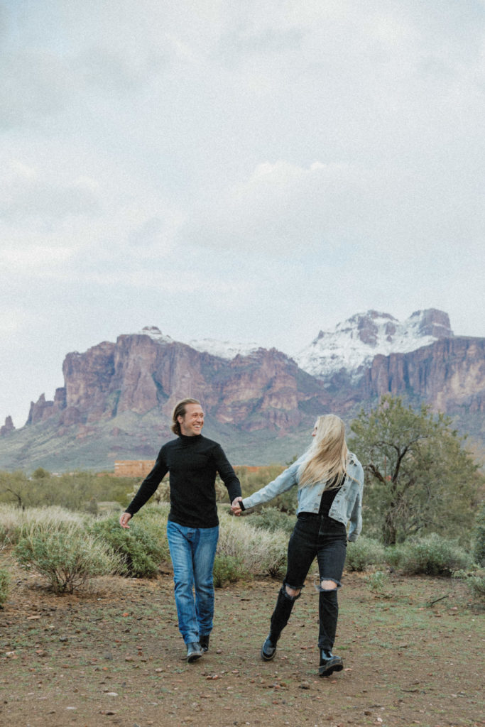 Couple walking in front of the Superstition Mountains 