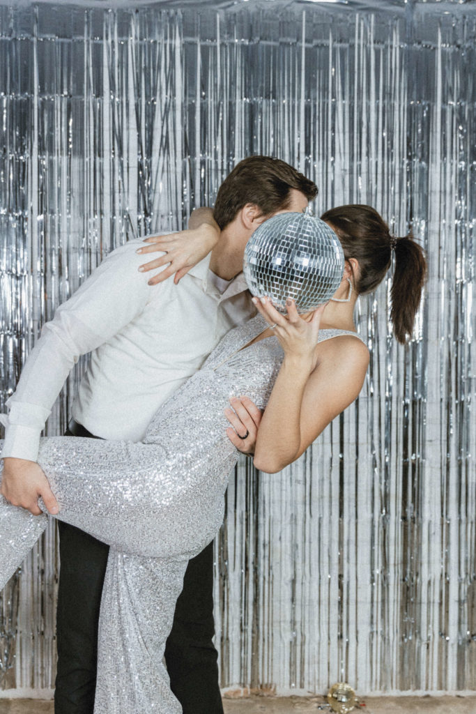 couple kissing in front of a disco ball 