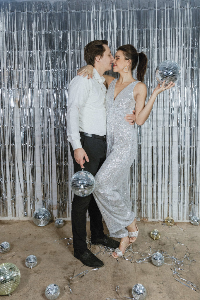 couple face to face and holding disco balls 
