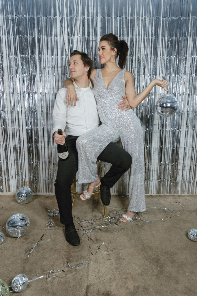 couple posing with champagne and disco balls 