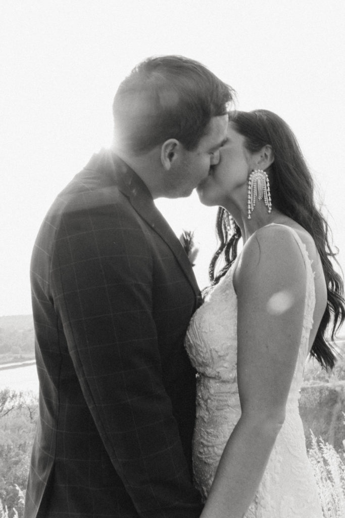 black and white photo of bride and groom kissing 