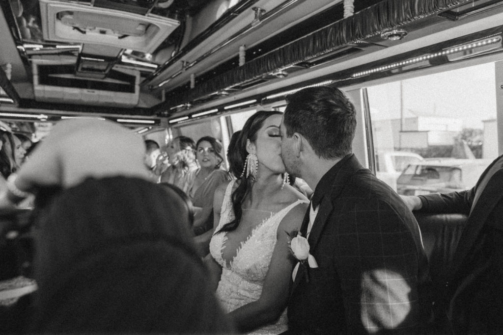 bride and groom kissing on partying bus 