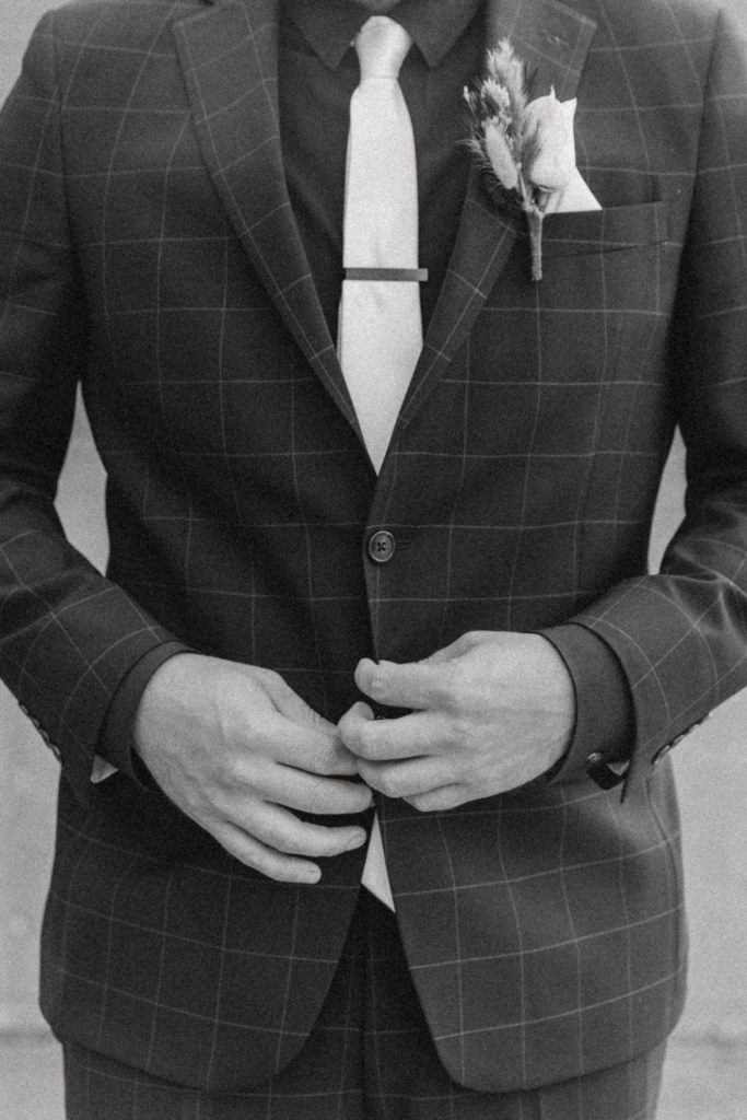detail picture of groom adjusting his suit 