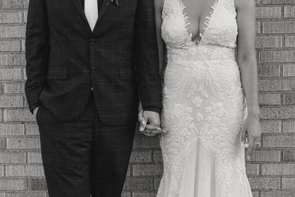 black and white details photo of bride and groom holding hands 