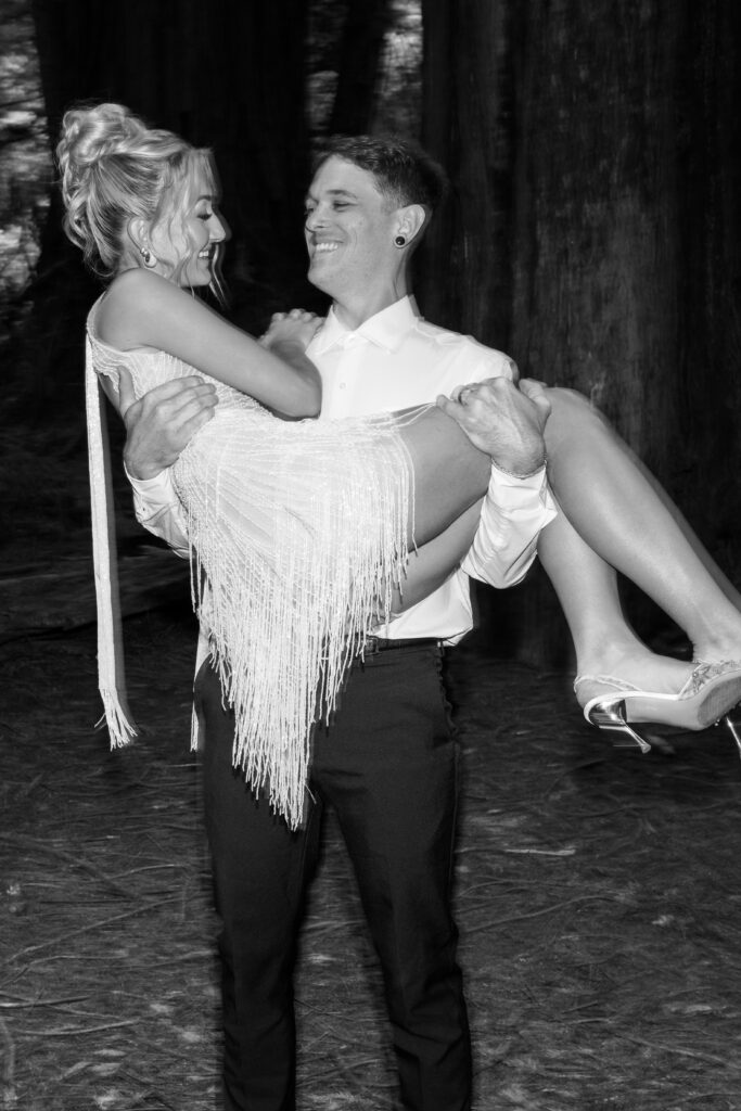 groom picking up bride in the redwoods